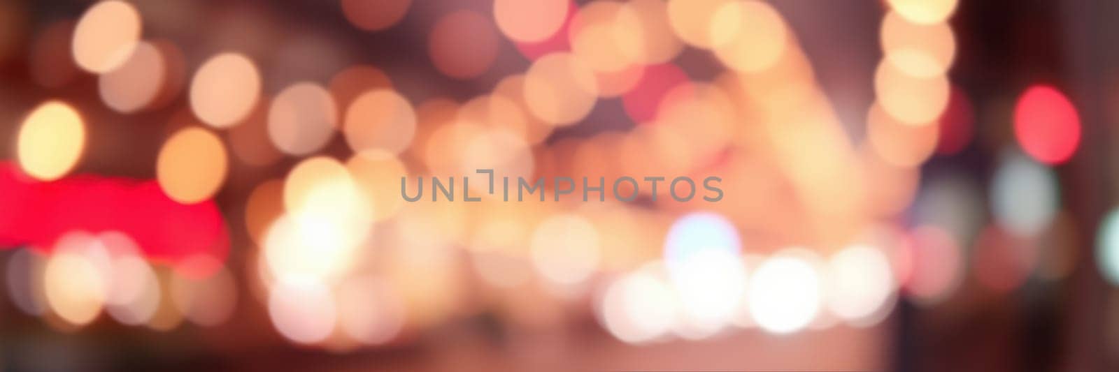Colorful bokeh lights illuminate the city streets as people gather for a nighttime celebration. The vibrant atmosphere is filled with excitement and joy as festivities unfold.