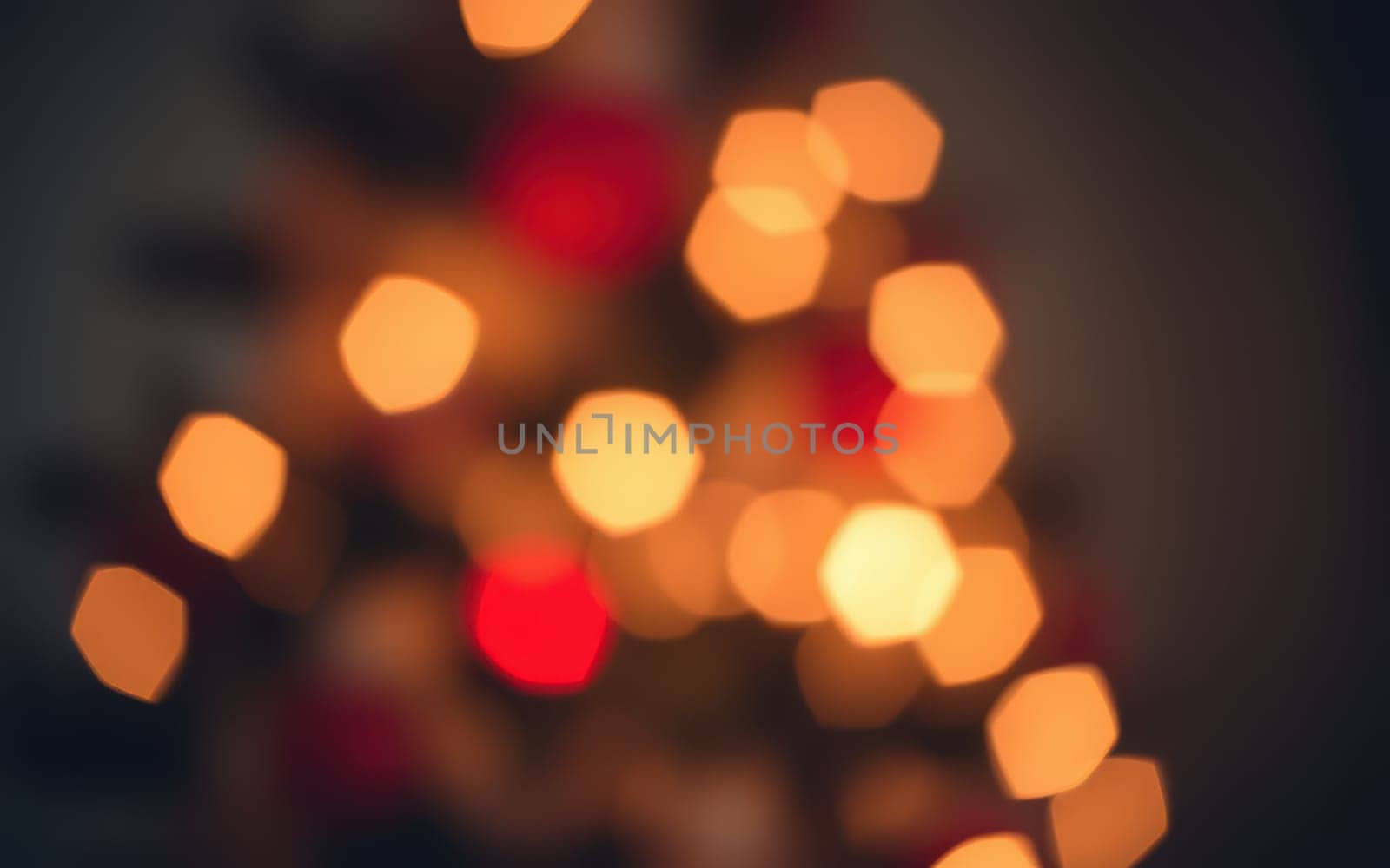 Colorful lights twinkle on a Christmas tree, casting a soft glow in a cozy room. The warm hues of red and yellow add to the holiday spirit, enhancing the festive ambiance.
