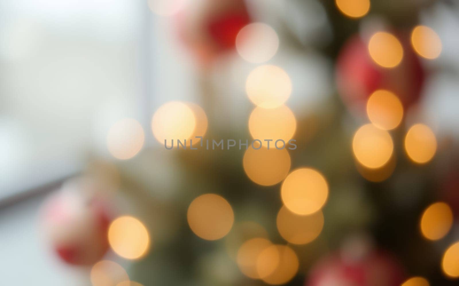 A beautiful Christmas tree adorned with twinkling lights and ornaments fills a cozy indoor space with a soft, inviting glow. The atmosphere is festive and cheerful.