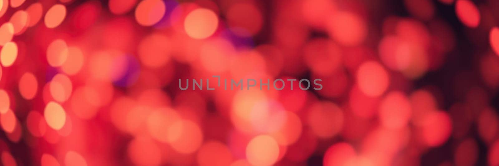Red bokeh lights fill the background, creating a warm and inviting atmosphere at a festive gathering held in the evening. The blurred lights enhance the celebratory mood.