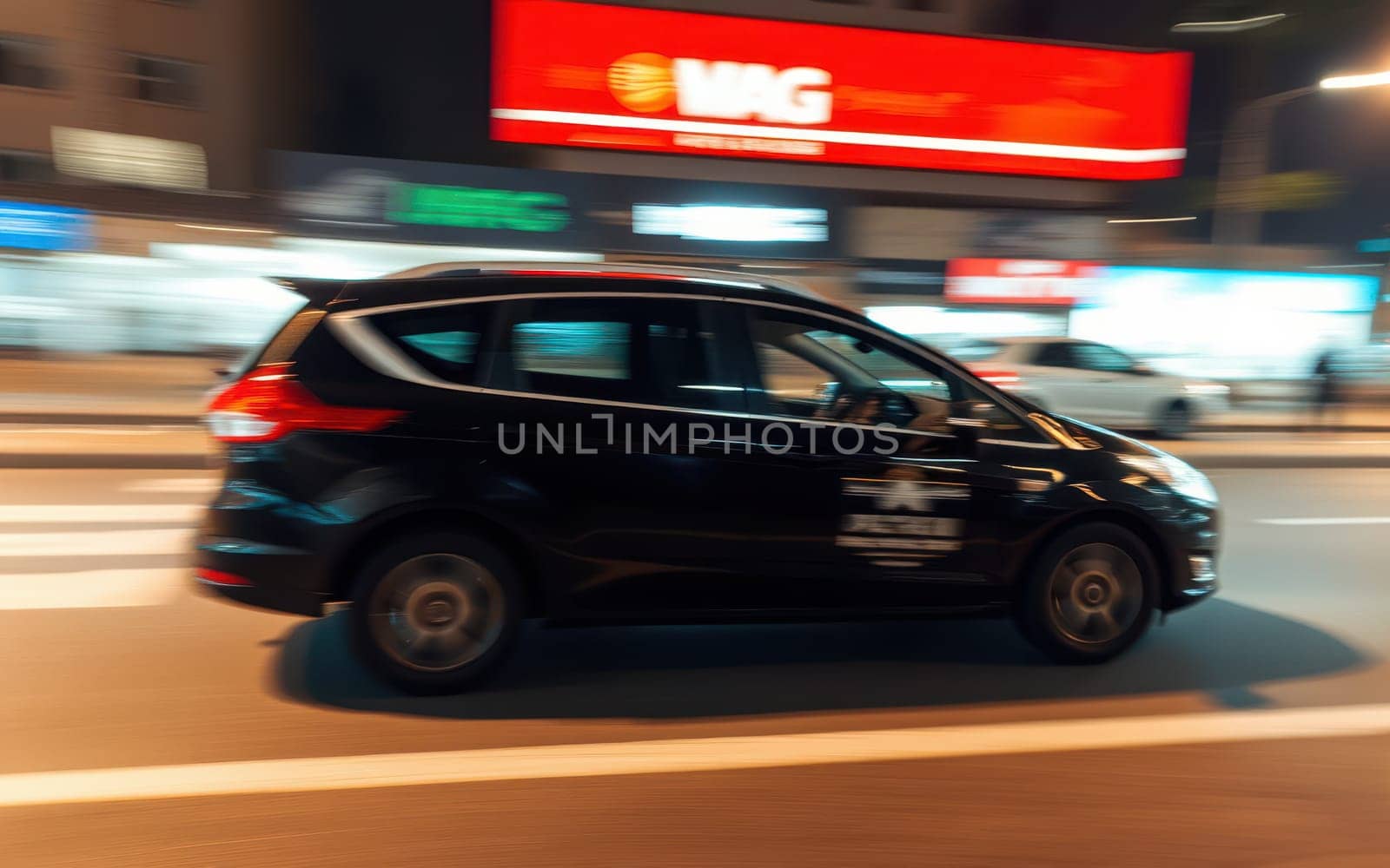 A black car is captured in motion, navigating through an illuminated city street filled with vibrant neon signs and lights at night.