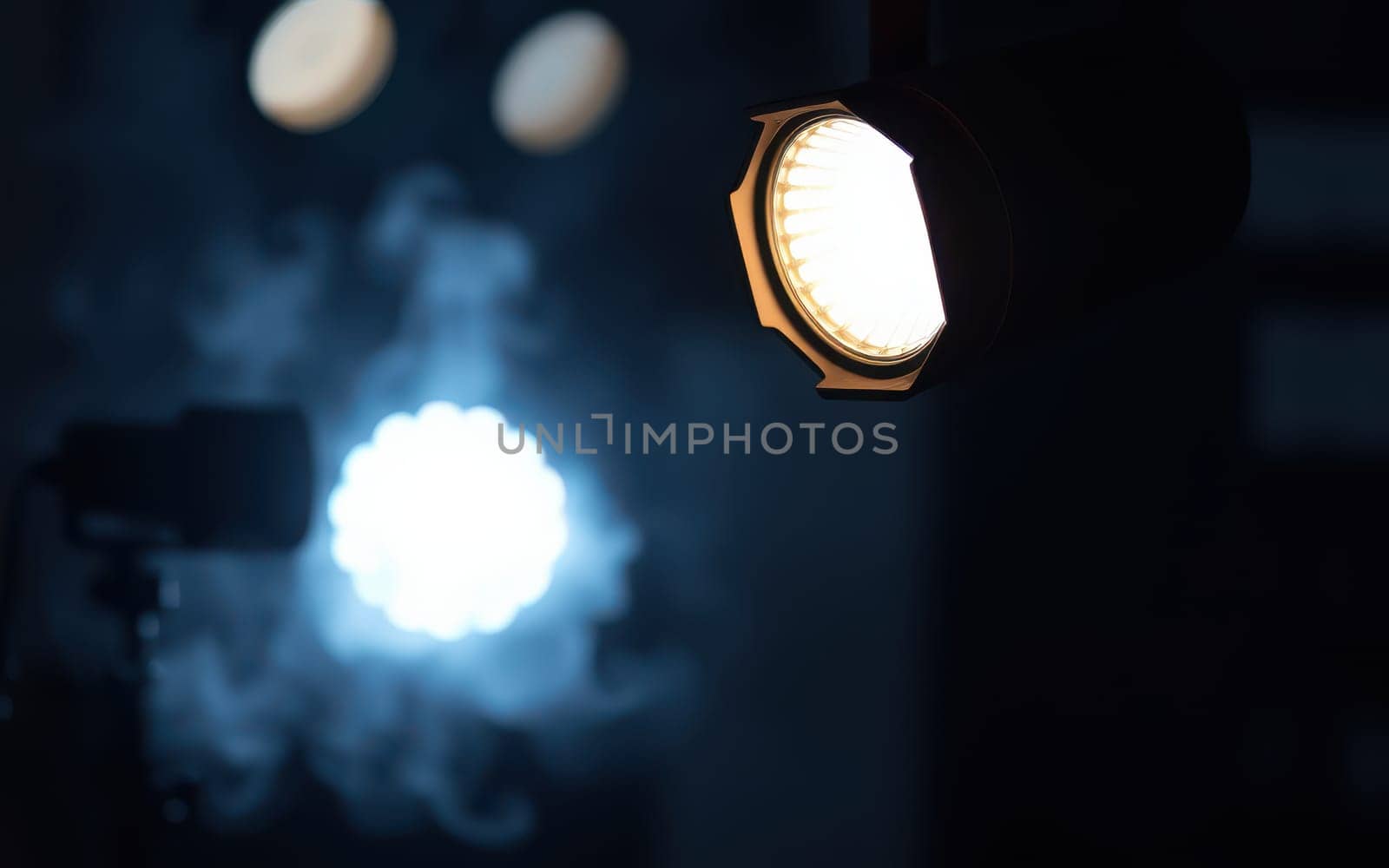 Bright stage lights illuminate a smoky background, creating a dramatic atmosphere. The contrasting shades enhance the mysterious mood of the setting.