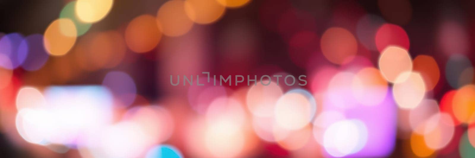 Bright, colorful bokeh lights fill the scene, creating a lively atmosphere in a busy city during nighttime. The blurred lights suggest movement and energy.