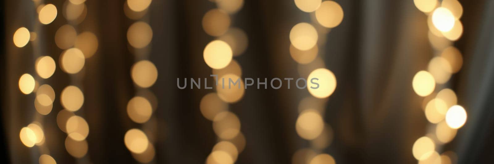 Soft glowing lights drape gracefully in a cozy indoor space, creating a warm ambiance for an evening gathering. The dreamy bokeh effect enhances the inviting atmosphere.