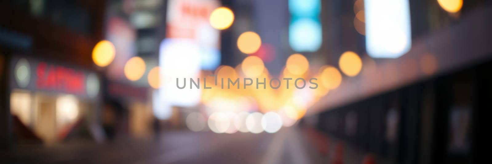 A busy city street comes alive at night with vibrant lights creating a festive atmosphere. People can be seen walking amidst glowing billboards and storefronts.