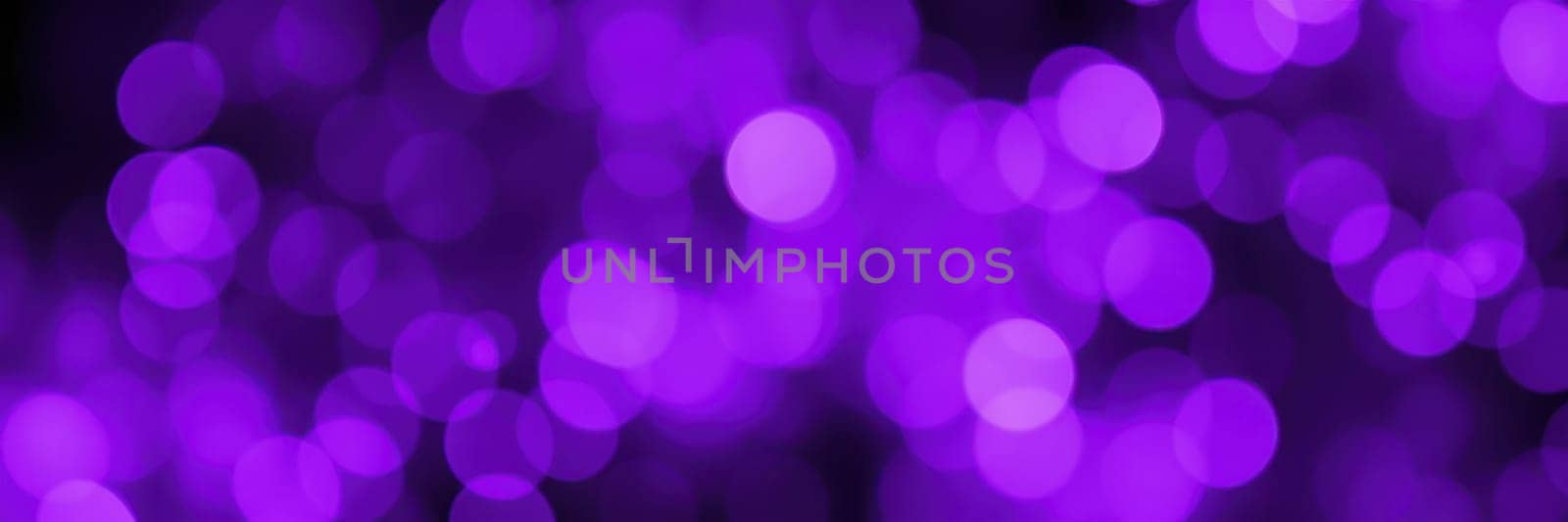 Soft purple bokeh lights illuminate the setting, enhancing the ambiance during an evening gathering. The blurred circles suggest a joyful and vibrant atmosphere.