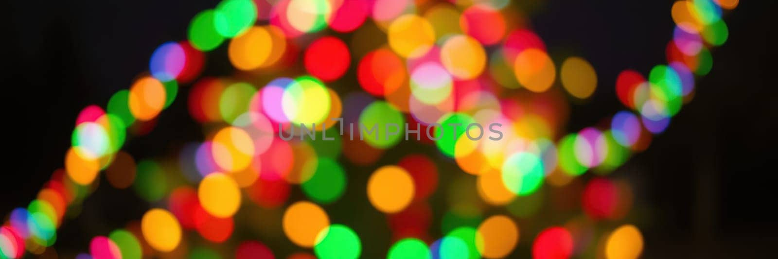 A beautifully decorated holiday tree sparkles with vibrant colored lights in a winter evening setting, evoking the joy of seasonal festivities and togetherness.