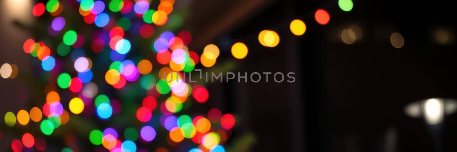Bright and colorful lights adorn a Christmas tree, creating a warm and inviting atmosphere in a cozy indoor space filled with holiday cheer.