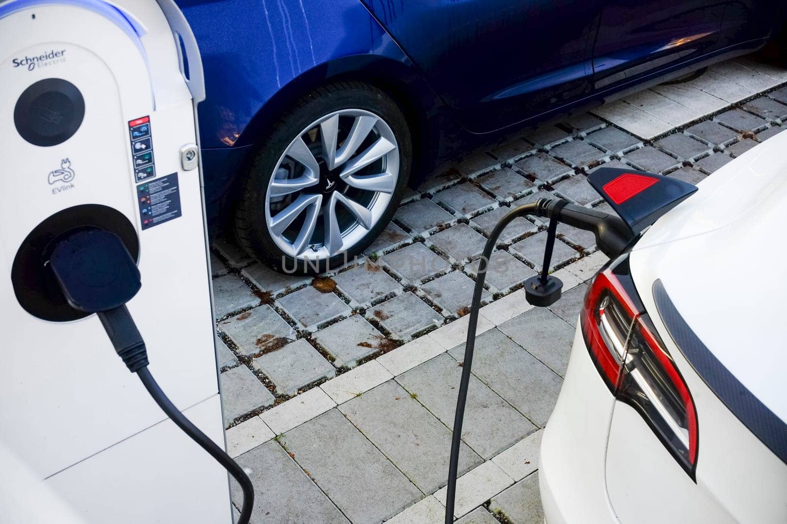 Cremona, Itally - October 6th 2024 White tesla model 3 long range dual motor all-wheel drive charging its battery at a schneider electric evlink charging station