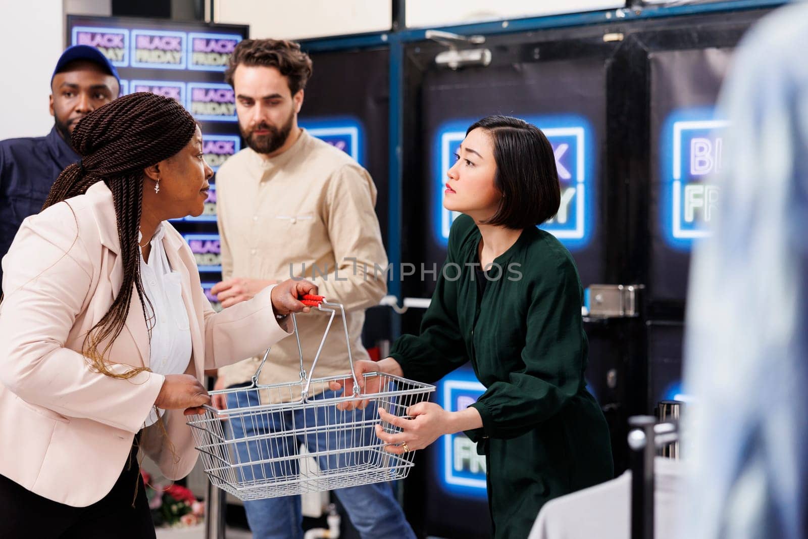 Black Friday madness. Stressed people shoppers pulling shopping basket while hunting for bargains, arguing during seasonal sales, two angry women fighting in store, bargain hunting
