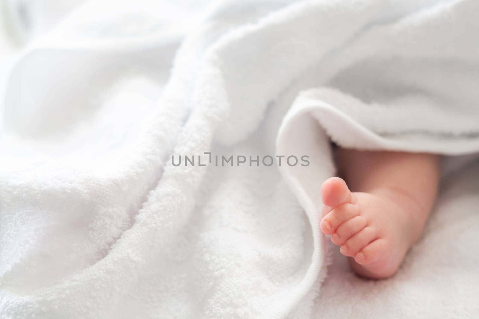 Essence of innocence as a newborn's foot gently tiptoes out from a snug white towel