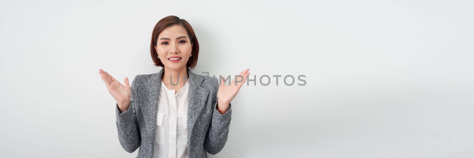 Happy young Asian businesswoman wearing gray suit clapping isolated on white banner background by makidotvn