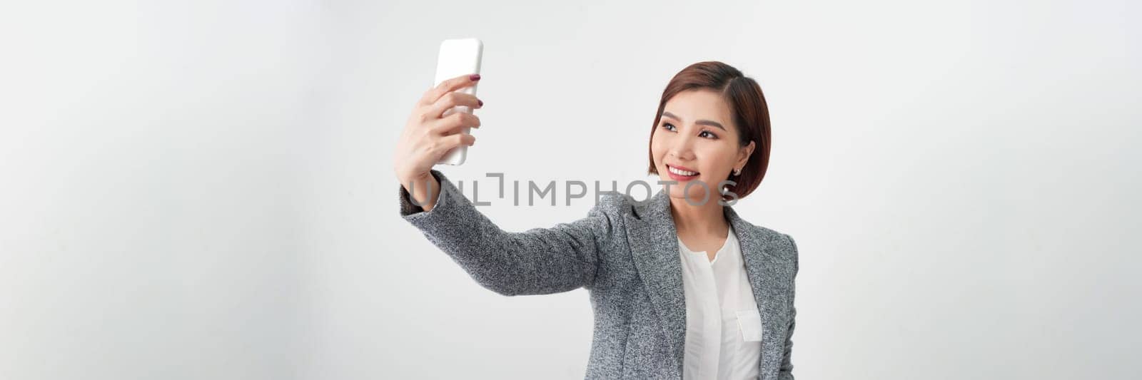 young businesswoman taking selfie with cellphone on gray banner