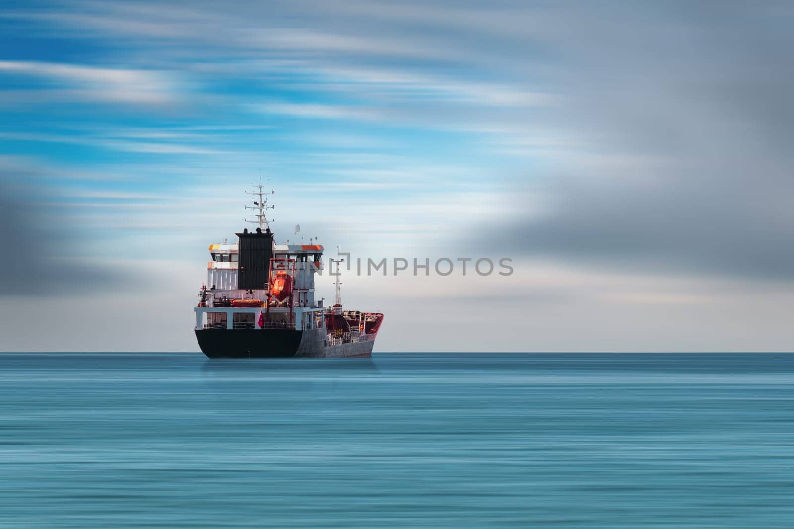 Transport ship traveling in open sea in cloudy weather. by Sonat