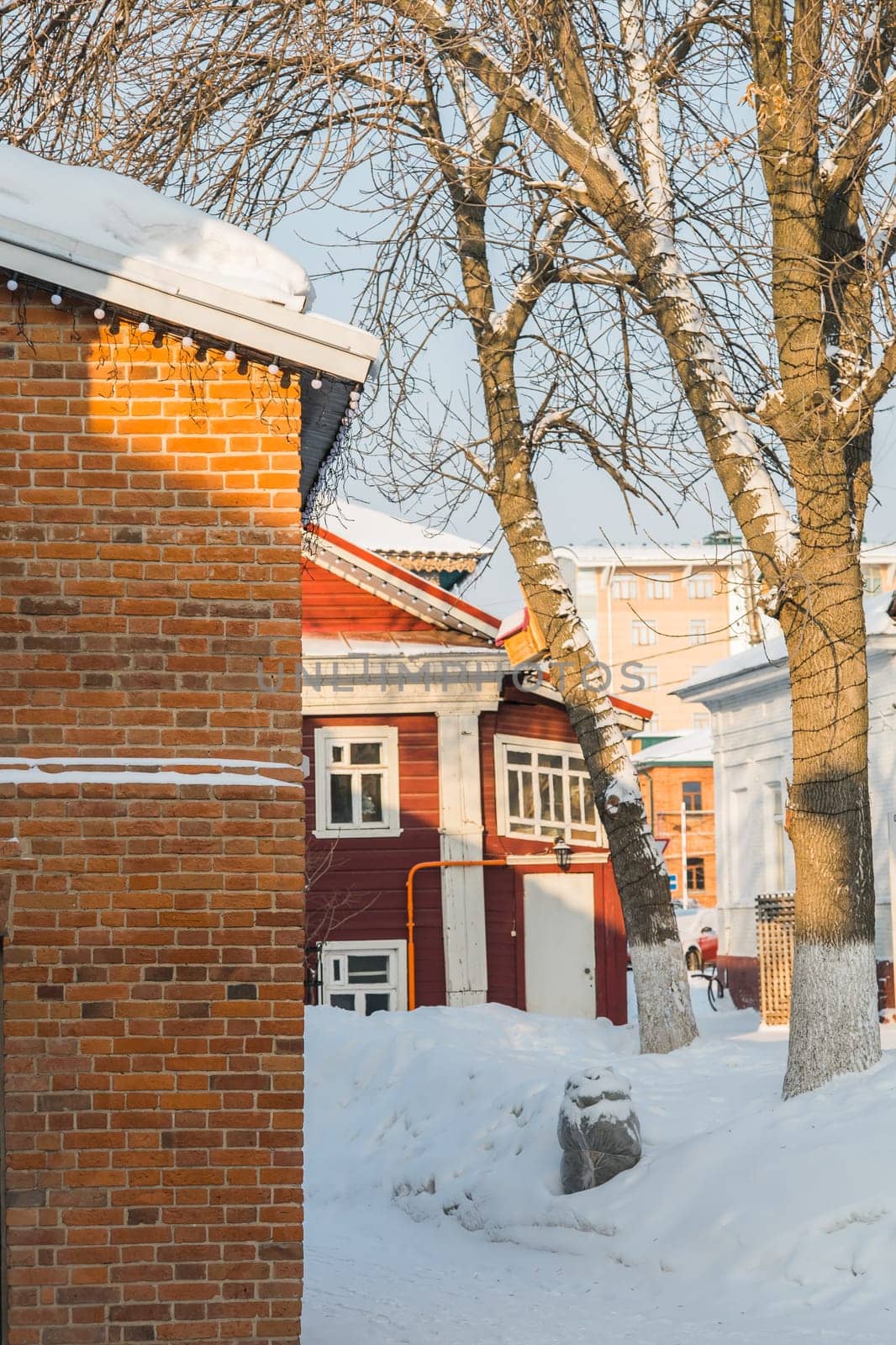 Exterior design of wooden red cottage in snowy town. Winter street with small buildings, cold season in city by Satura86