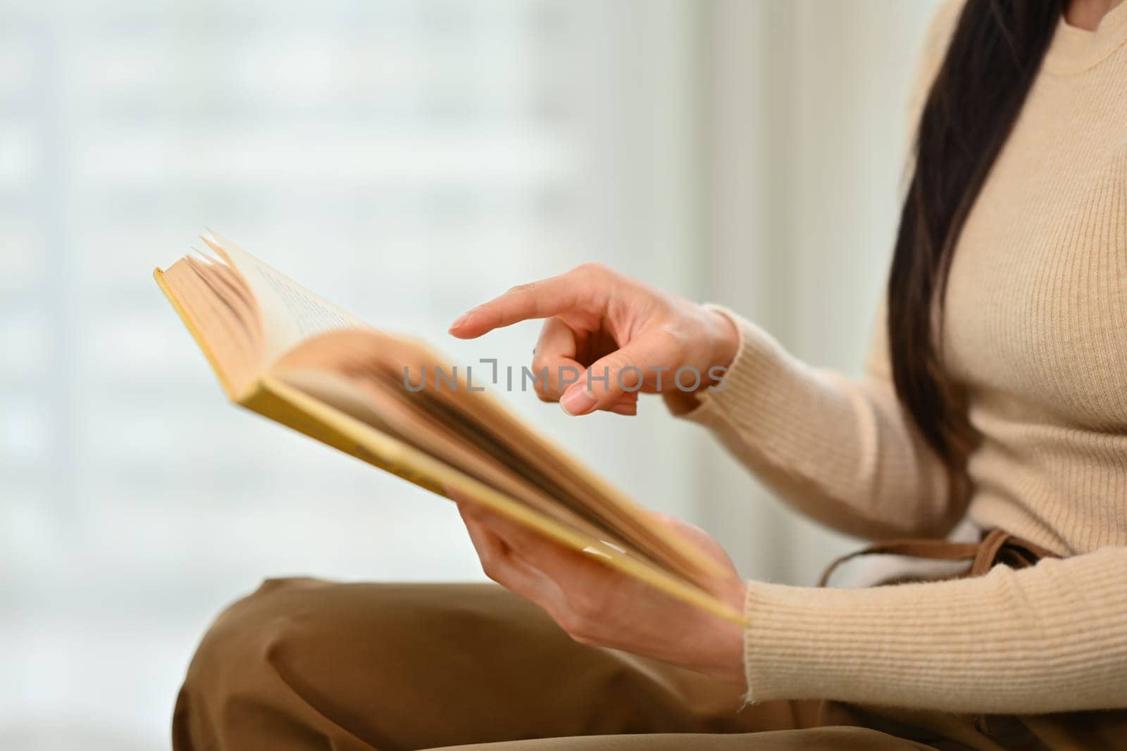 Cropped image of young woman in casual clothes reading book at home. People, leisure and lifestyle concept.