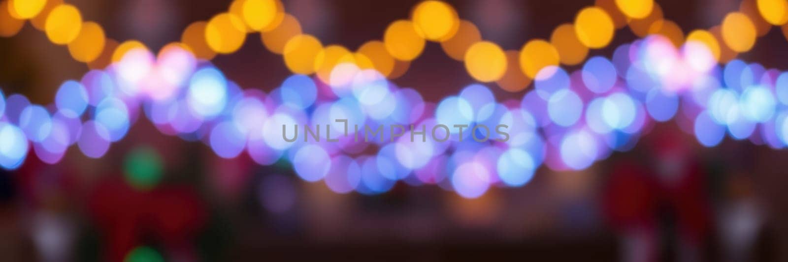 Brightly colored lights hang overhead, creating a vibrant and cheerful atmosphere in an outdoor area filled with decorations and people celebrating together at night.