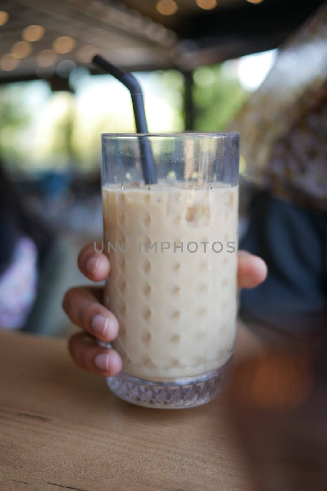 A chilled drink is typically served in a glass filled with ice and a straw inserted into it