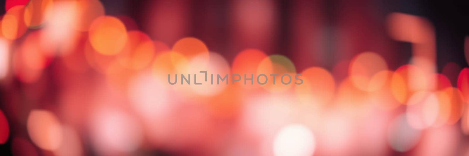 Bright, soft lights blur together, creating a warm and inviting ambiance in the heart of a city at night. The vibrant colors enhance the festive mood among the crowd.