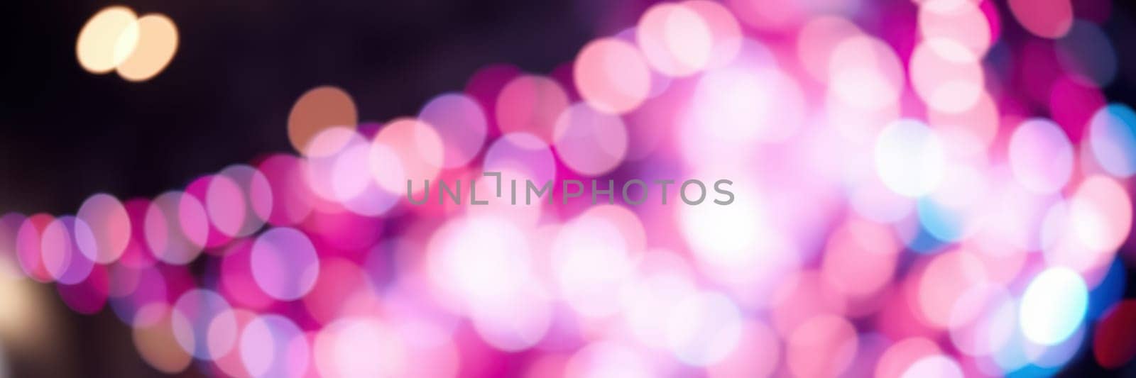 A myriad of colorful lights blurs into bokeh shapes, illuminating an urban area filled with excitement and energy. The vibrant display enhances the lively atmosphere of the evening.