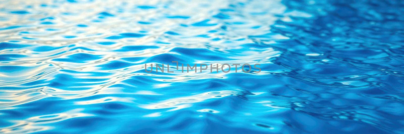Calm waters exhibit a mesmerizing pattern of gentle ripples under bright daylight, reflecting a soothing array of blue hues in a peaceful environment.