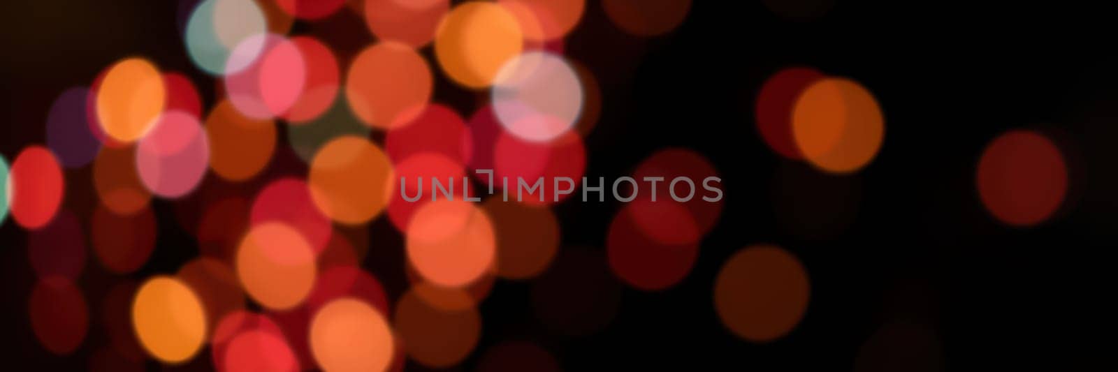 Bright, colorful lights form a bokeh effect against a dark background, creating a lively atmosphere perfect for a night celebration in an urban setting.