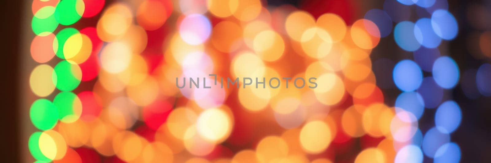 Brightly colored lights in various hues blur together, casting a warm glow and enhancing the joyful ambiance of a holiday celebration. The scene suggests excitement and festivity.