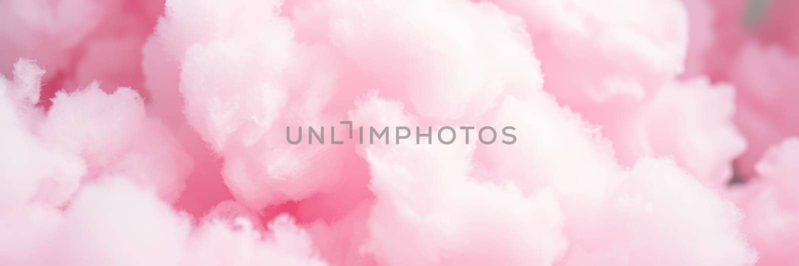 Fluffy pink cotton candy clouds dominate the sky during a vibrant summer fair. Families enjoy the festivities below as the sun shines brightly on the scene.