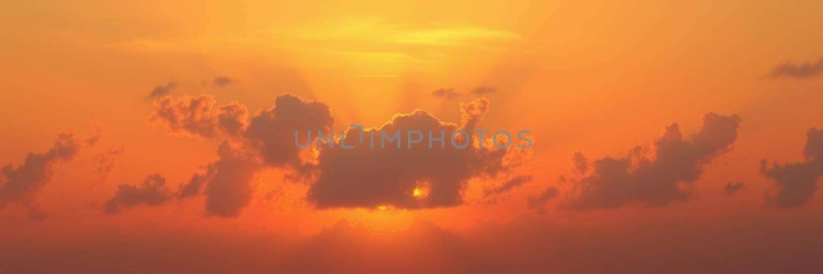 A stunning sunset unfolds over the ocean, with golden clouds illuminated by the warm light. Rays of sunlight pierce through the clouds, creating a tranquil atmosphere.