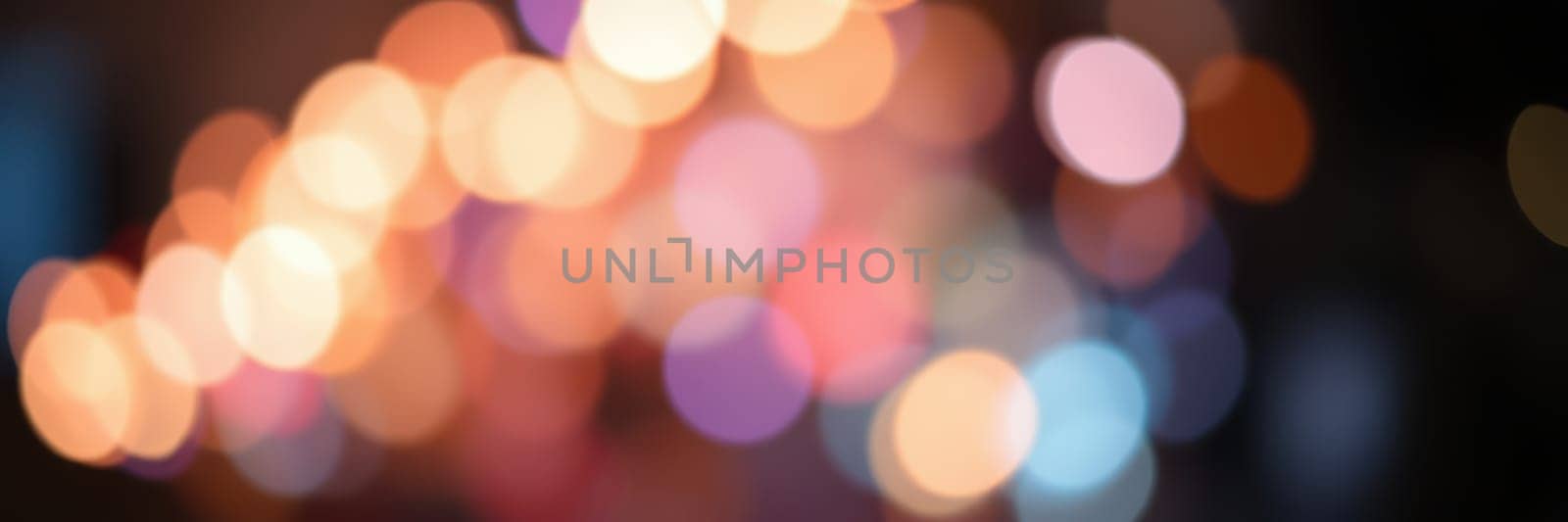 A vibrant display of blurred bokeh lights fills the urban landscape, adding a joyful ambiance to the night. The colorful orbs create a mesmerizing effect, enhancing the lively scene.
