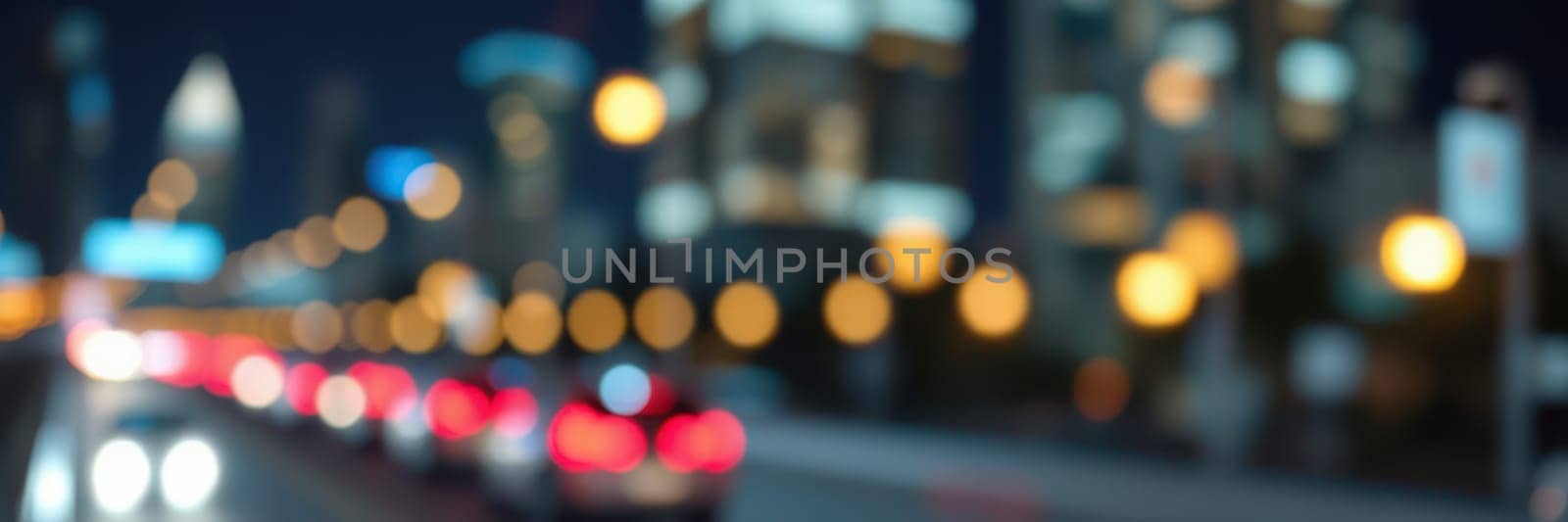 Cars are lined up in traffic on a city street at night, illuminated by the vibrant lights of skyscrapers and glowing street lamps. The atmosphere is lively and energetic.