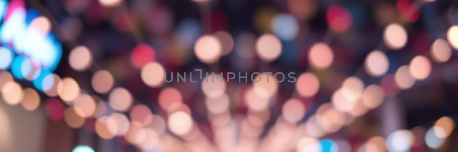 Bright, blurred lights fill the background, enhancing the cheerful vibe of a nighttime gathering in a vibrant city. The atmosphere is filled with excitement and joy.