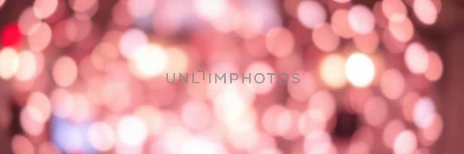 Soft, shimmering lights fill the area, creating a magical ambiance for the evening gathering. People move about, celebrating together amidst the beautiful display of warm colors.