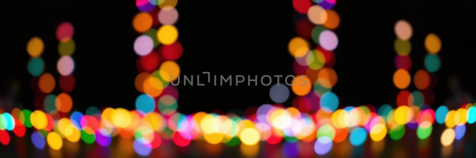 Bright, out-of-focus lights illuminate the surroundings, providing a vibrant and cheerful backdrop for a nighttime gathering in an urban environment.