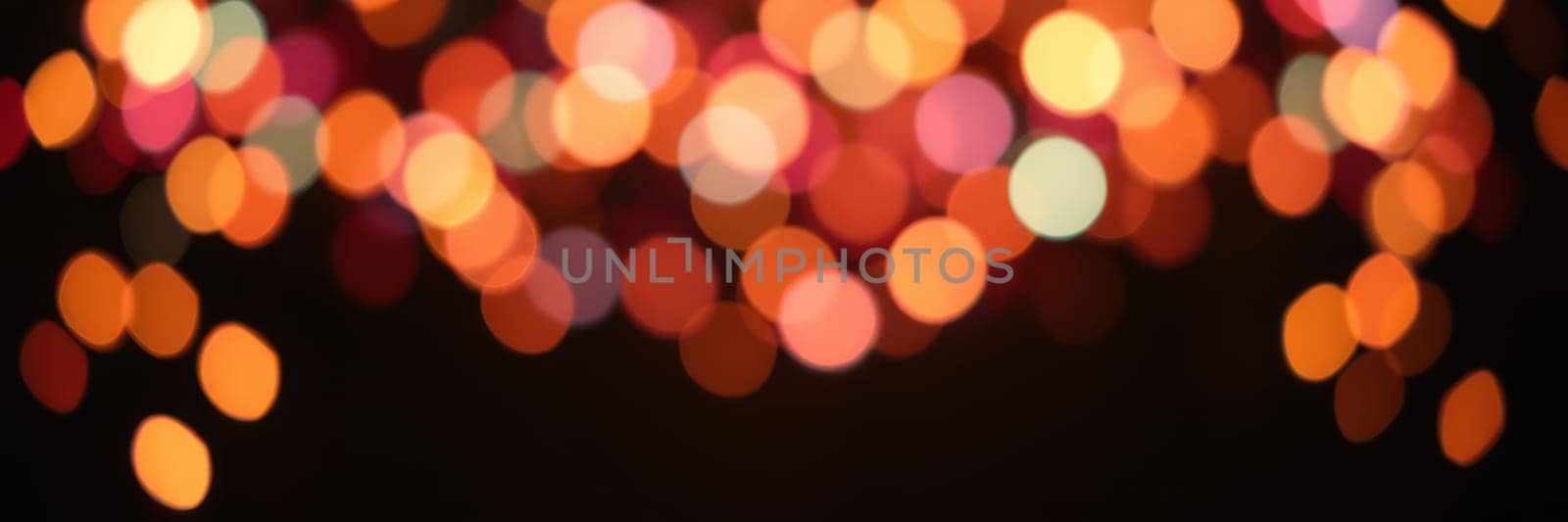A dazzling display of blurred bokeh lights in vibrant colors decorates the evening sky, enhancing the joyful ambiance of a lively celebration or event.