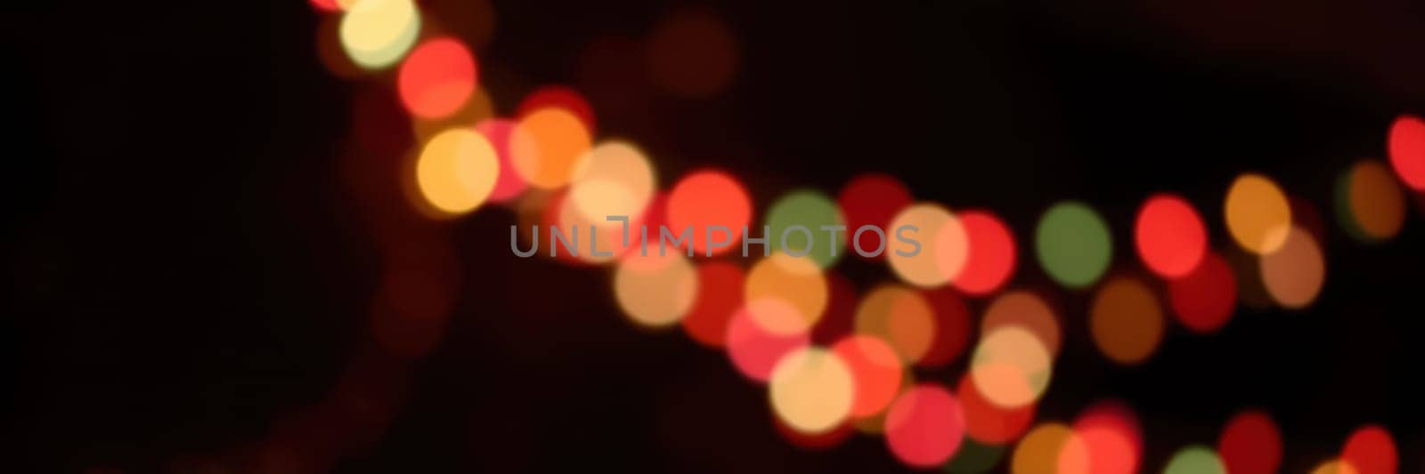 Bright string lights emit a warm glow in various colors, enhancing the festive ambiance of an evening gathering. The blurred background adds depth and charm to the scene.