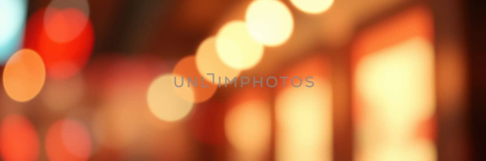 Colorful bokeh lights illuminate a street, enhancing the evening ambiance with a warm glow. The blurred effect creates a dreamlike quality, making the urban landscape inviting.