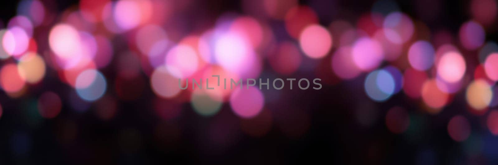 Soft, blurred lights in shades of pink, blue, and purple create a captivating atmosphere at a nighttime event. The vibrant colors enhance the festive mood of the celebration.