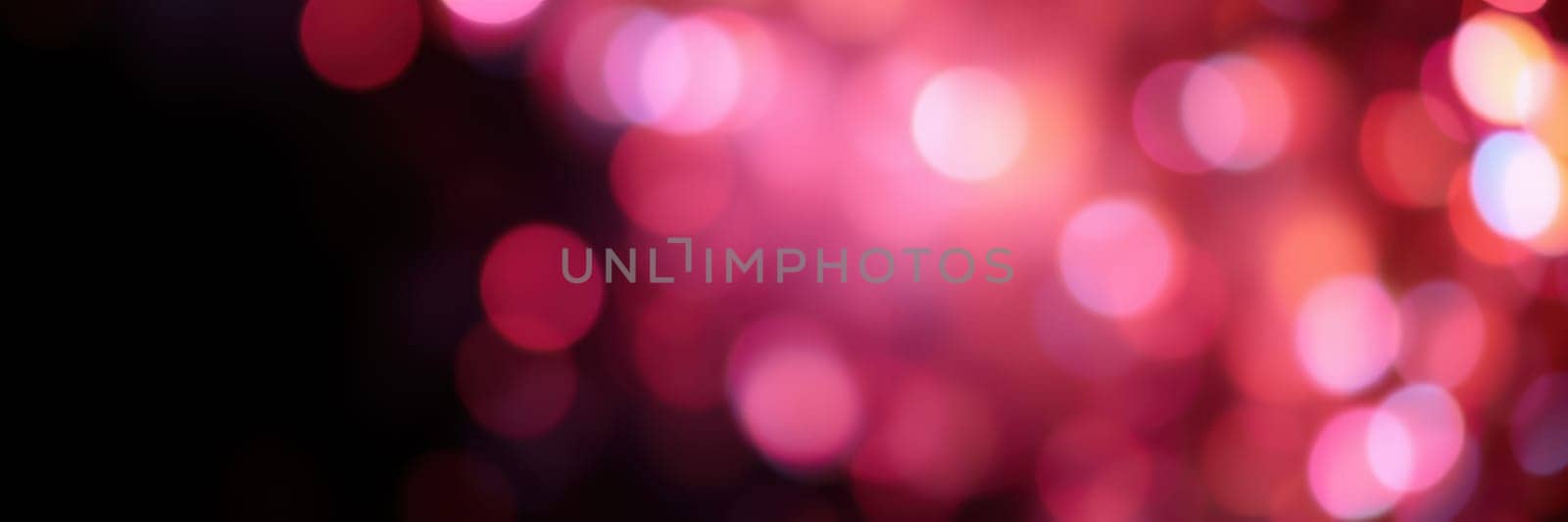 Colorful bokeh lights in shades of pink illuminate the night, enhancing the festive mood of a city celebration. The soft glow adds warmth and excitement to the surroundings.