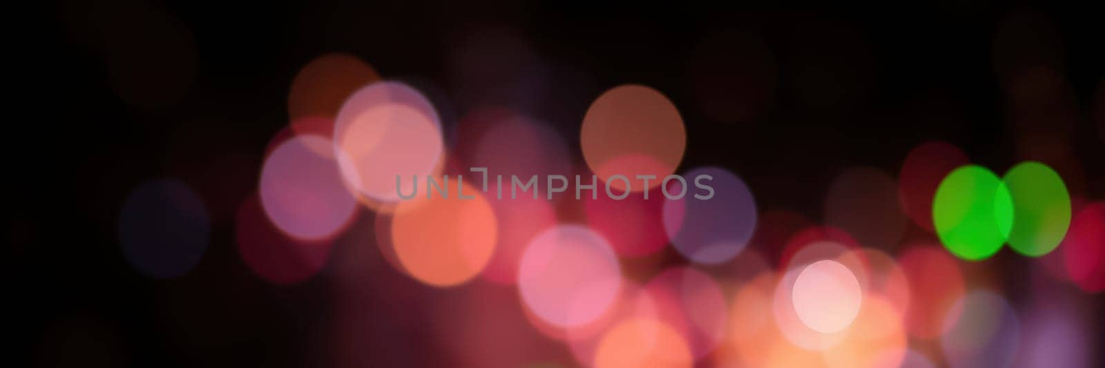 Vibrant bokeh lights illuminate the background during a lively evening celebration, with various colors blending together to create an enchanting ambiance.