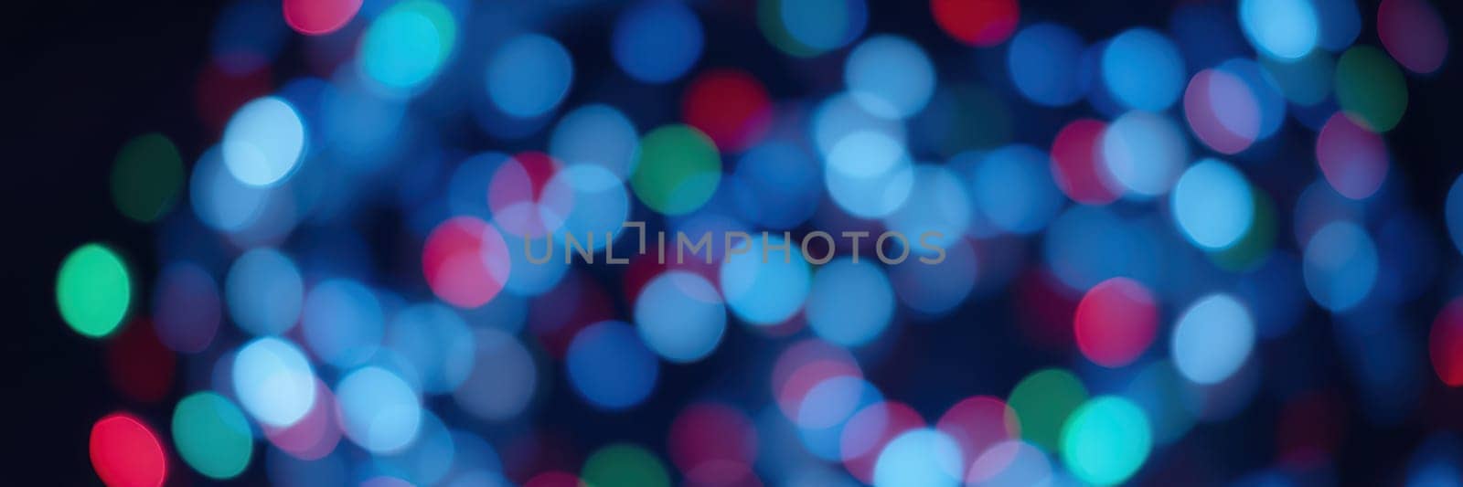 Blurred colorful lights in shades of blue, red, and green illuminate the night, creating a vibrant and cheerful atmosphere for a holiday celebration.
