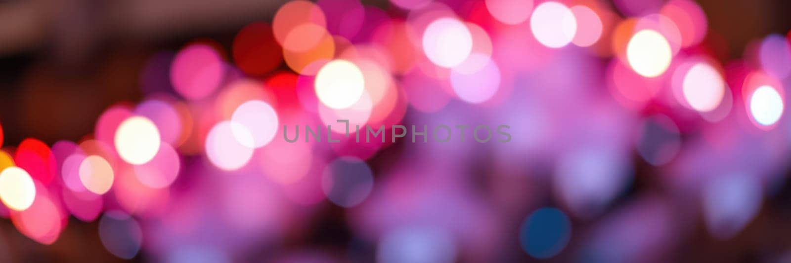 Bright, colorful lights form a beautiful bokeh effect, enhancing the festive atmosphere of an evening celebration in an urban setting. The vibrant hues add joy to the ambiance.