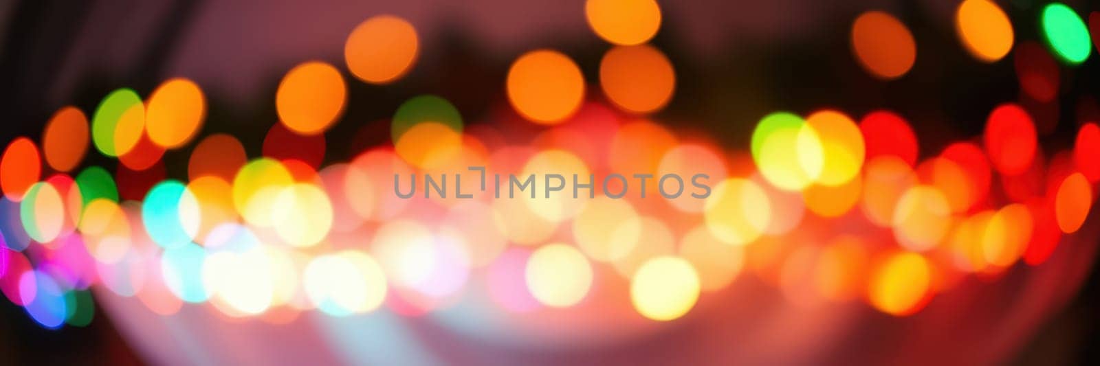 Brightly colored bokeh lights fill the background, creating a festive ambiance at a nighttime event. The warm hues suggest a cheerful gathering among friends and family.