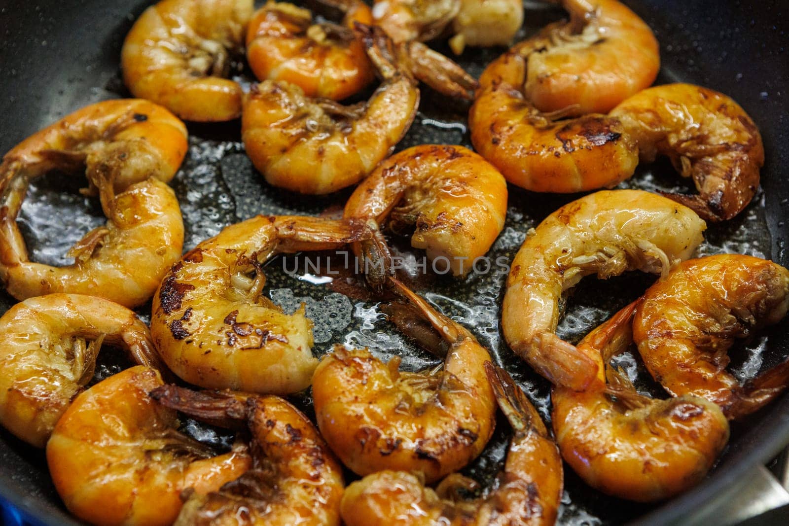 Golden pan-fried shrimp sizzling in a skillet, showcasing their rich, juicy texture and vibrant color. Ideal for use in cookbooks, restaurant menus, or gourmet advertisements