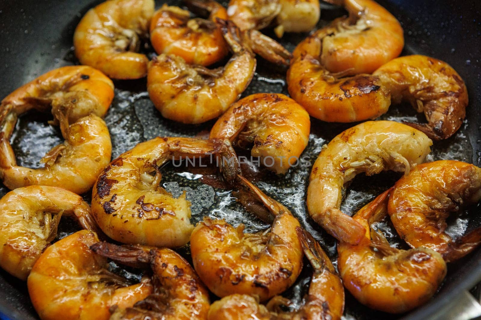 Golden pan-fried shrimp sizzling in a skillet, showcasing their rich, juicy texture and vibrant color. Ideal for use in cookbooks, restaurant menus, or gourmet advertisements