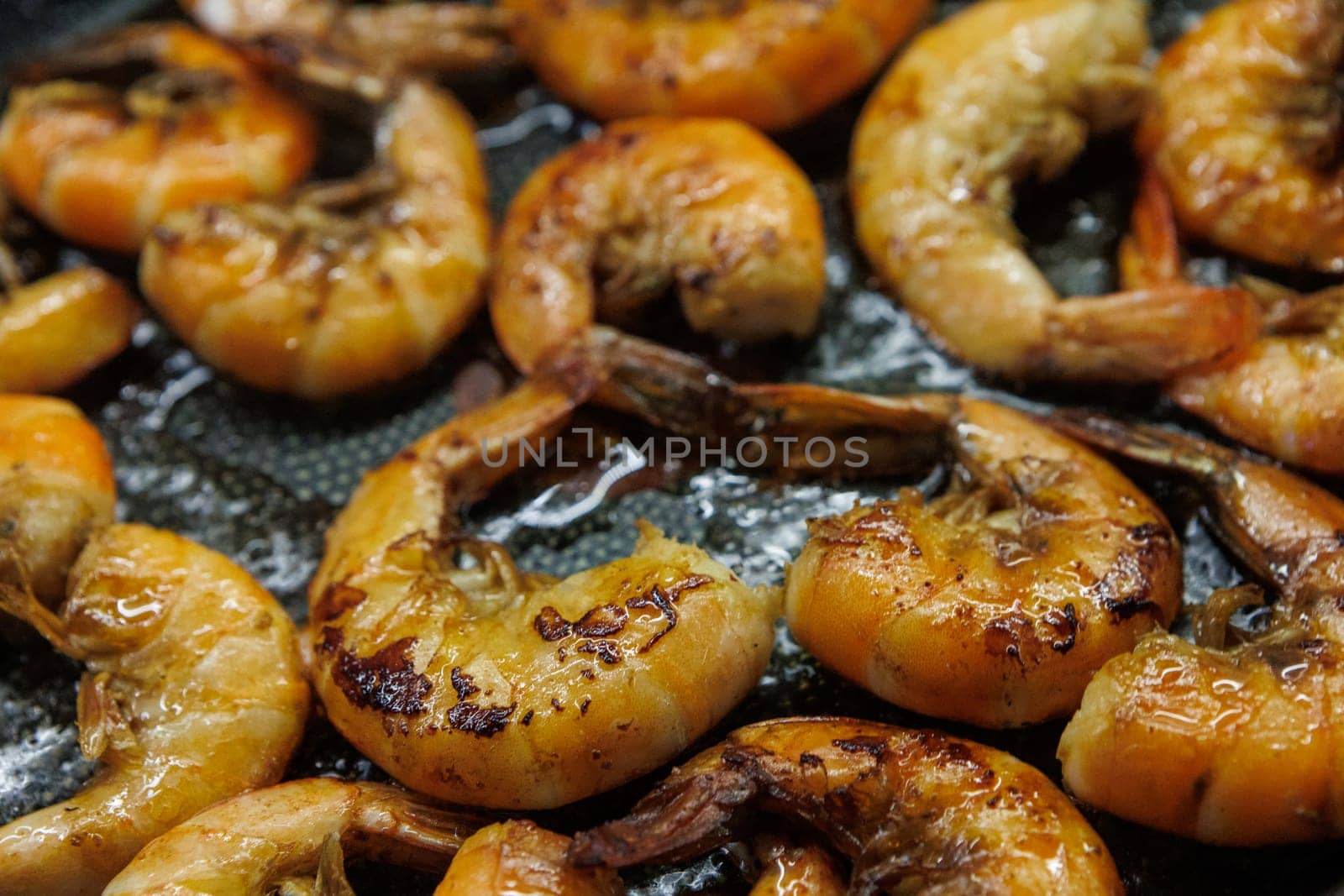 Golden pan-fried shrimp sizzling in a skillet, showcasing their rich, juicy texture and vibrant color. Ideal for use in cookbooks, restaurant menus, or gourmet advertisements