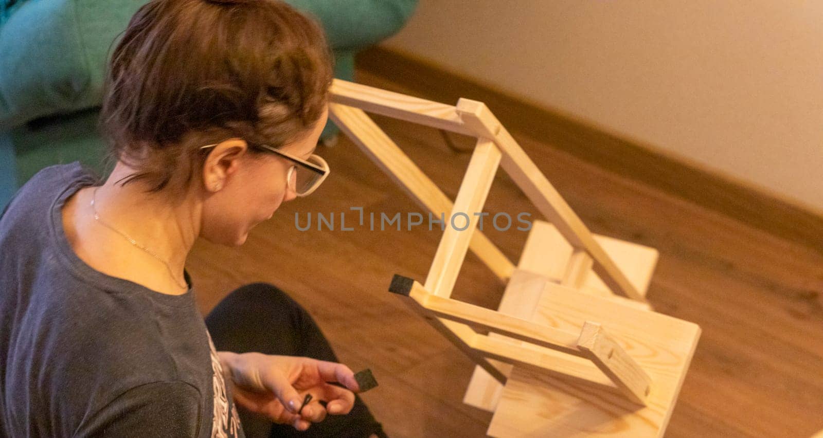 Woman is assembling wooden shelf