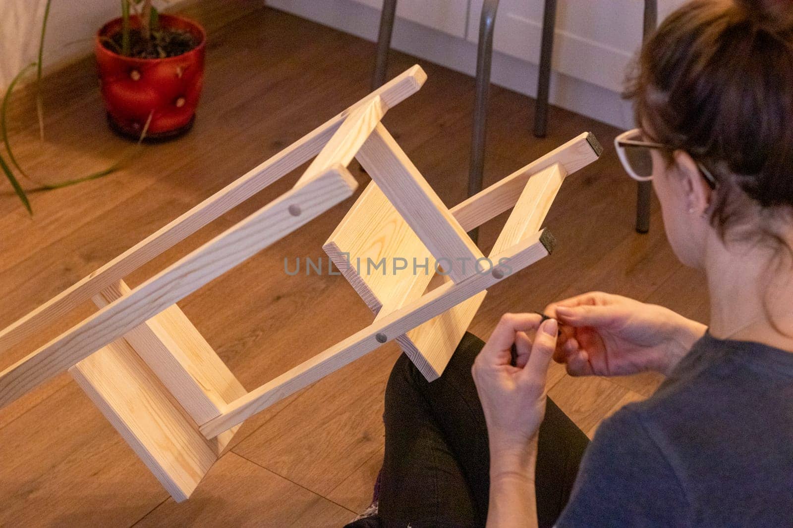 Woman is assembling wooden shelf