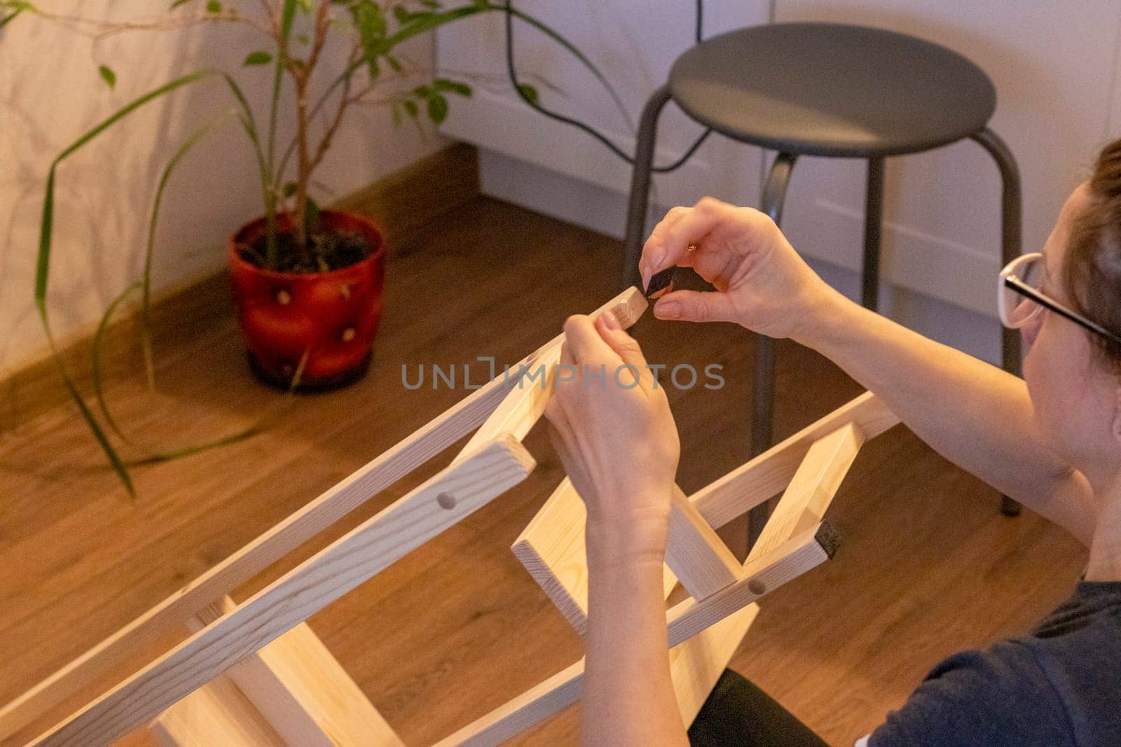 Woman is assembling wooden shelf