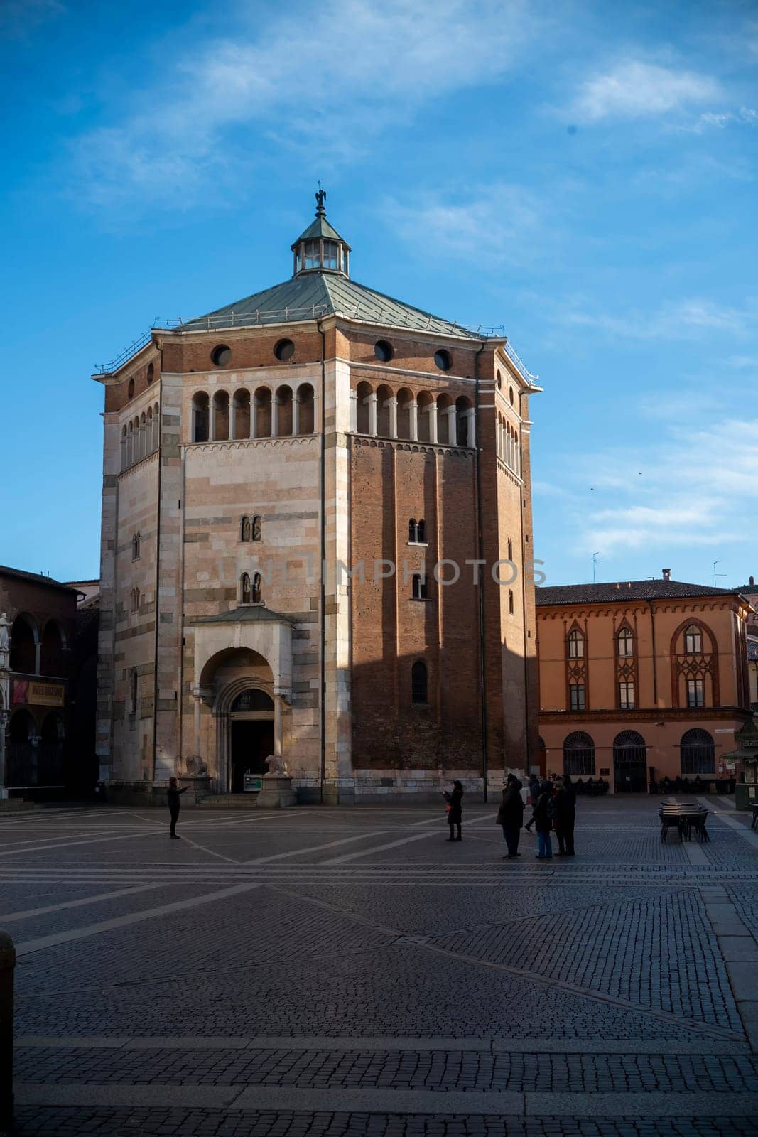 Cremona, Italy - November 27th 2024 Tourists taking pictures of the baptistery of cremona in piazza del comune, lombardy, on a sunny winter day
